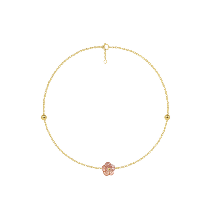 Gold anklet with a pink flower charm on a white background